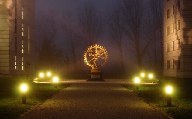 Statue of the dancing Shiva at CERN lit by ground lights on a foggy night
